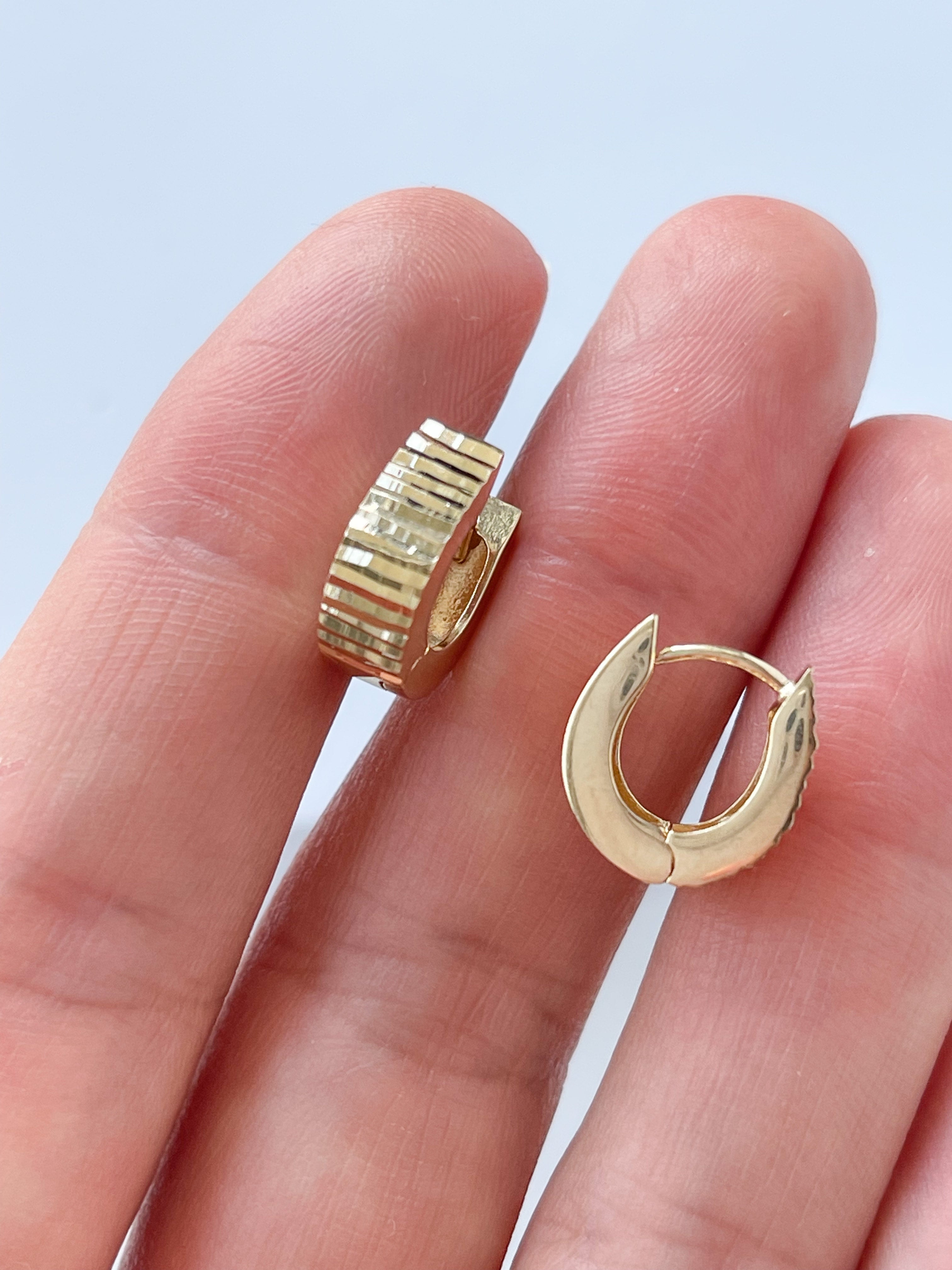 Model holding hoop earrings in 14K yellow gold.