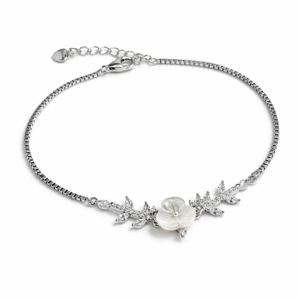 Silver bracelet with floral design and pearl on a white background