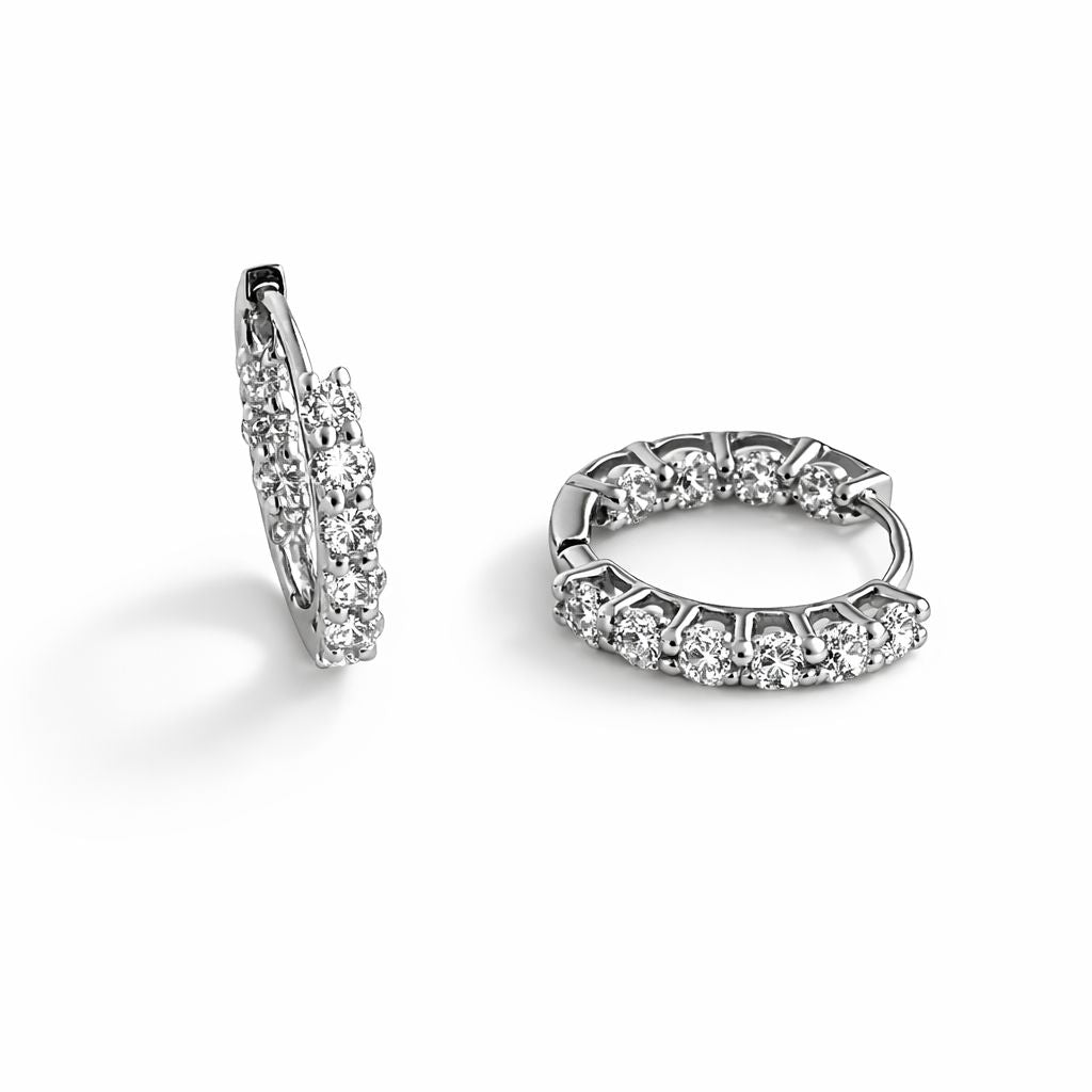 Pair of sterling silver hoop earrings with clear cubic zirconia on a white background