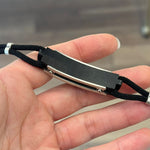 Hand holding a black and silver bracelet.