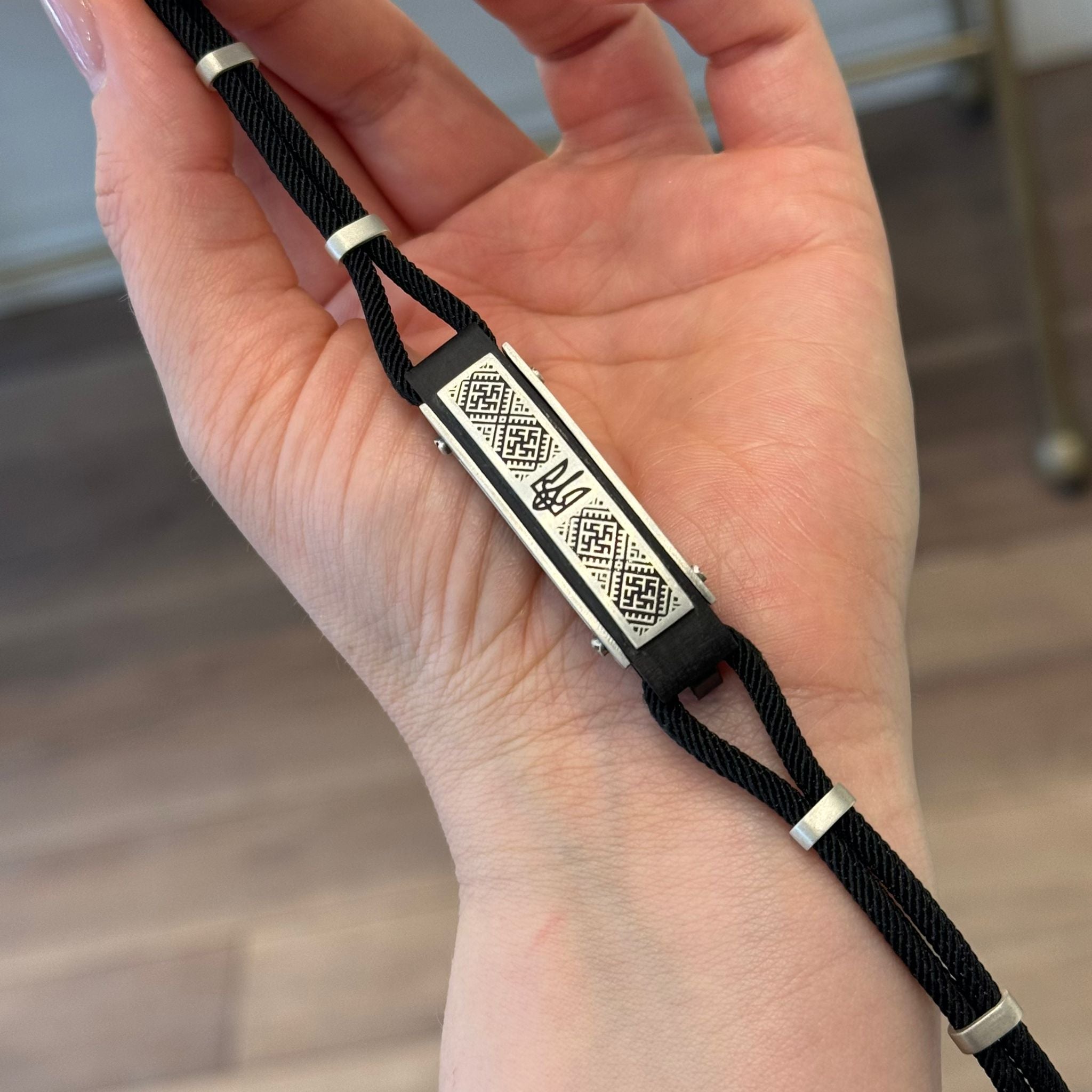 Hand holding a black braided cord with metallic accents