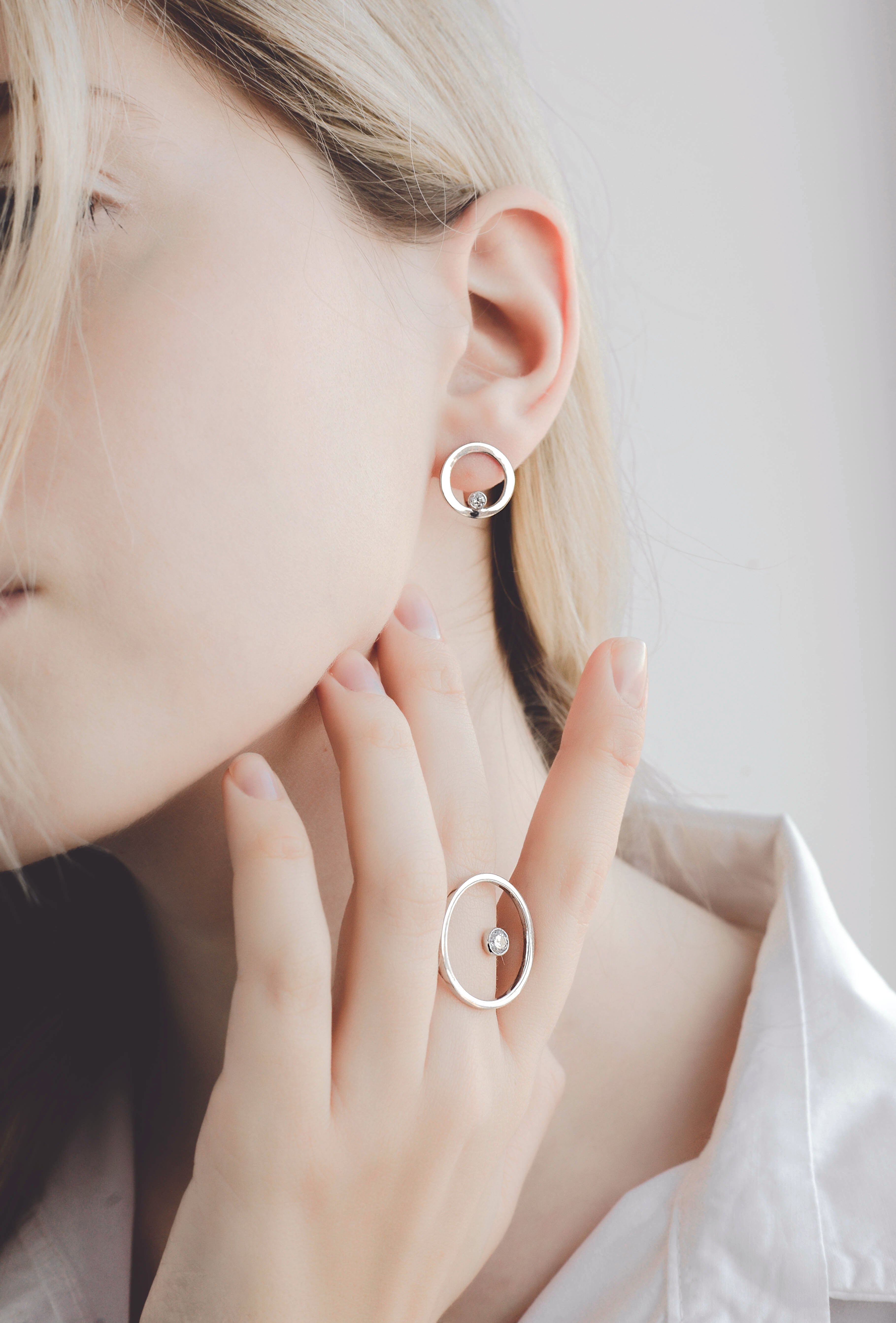 Model wearing set: lever back earrings in 14K white gold decorated with diamond-cut zirconium and 14K white gold ring decorated with zirconium.