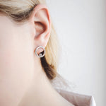 Model wearing lever back earrings in 14K white gold decorated with diamond-cut zirconium.