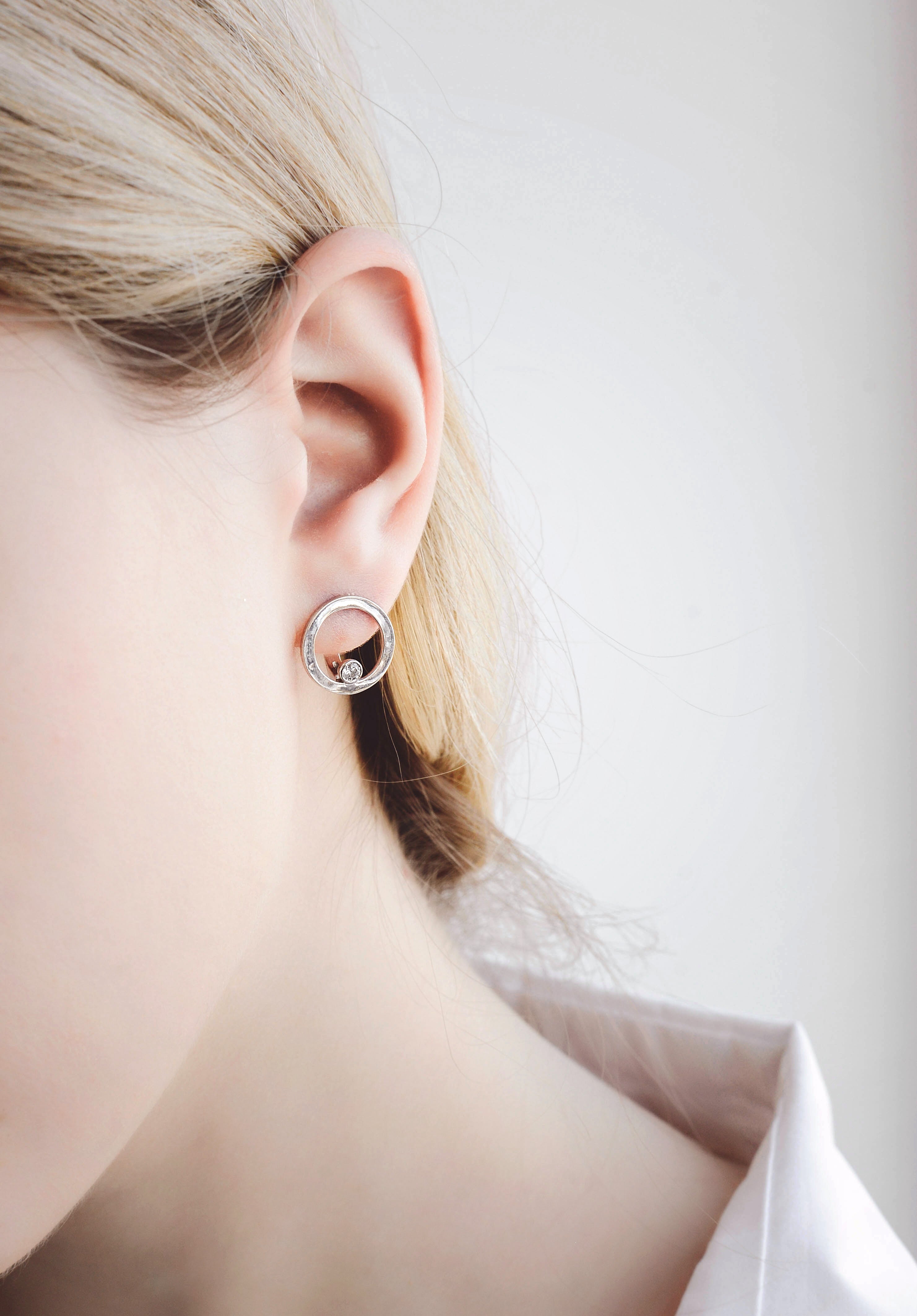 Model wearing lever back earrings in 14K white gold decorated with diamond-cut zirconium.
